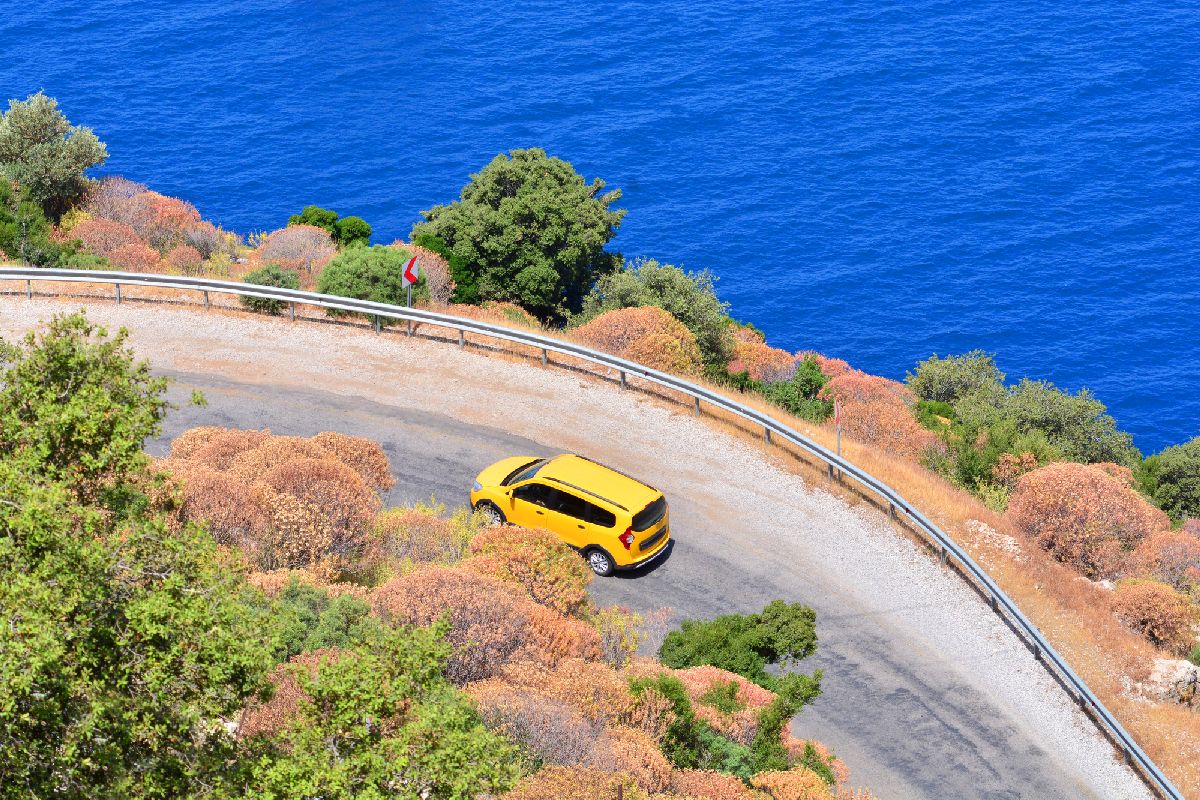 Car rental during the travel concept. Yellow car driving by the serpentine road over the sea. Beautiful mediterranean landscape.