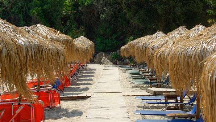 תקריב על שמשיות קש עבות ומיטות שיזוף על החוף ביוון, חוף אגיוס סראנטה (Agios Saranta) בפיליון