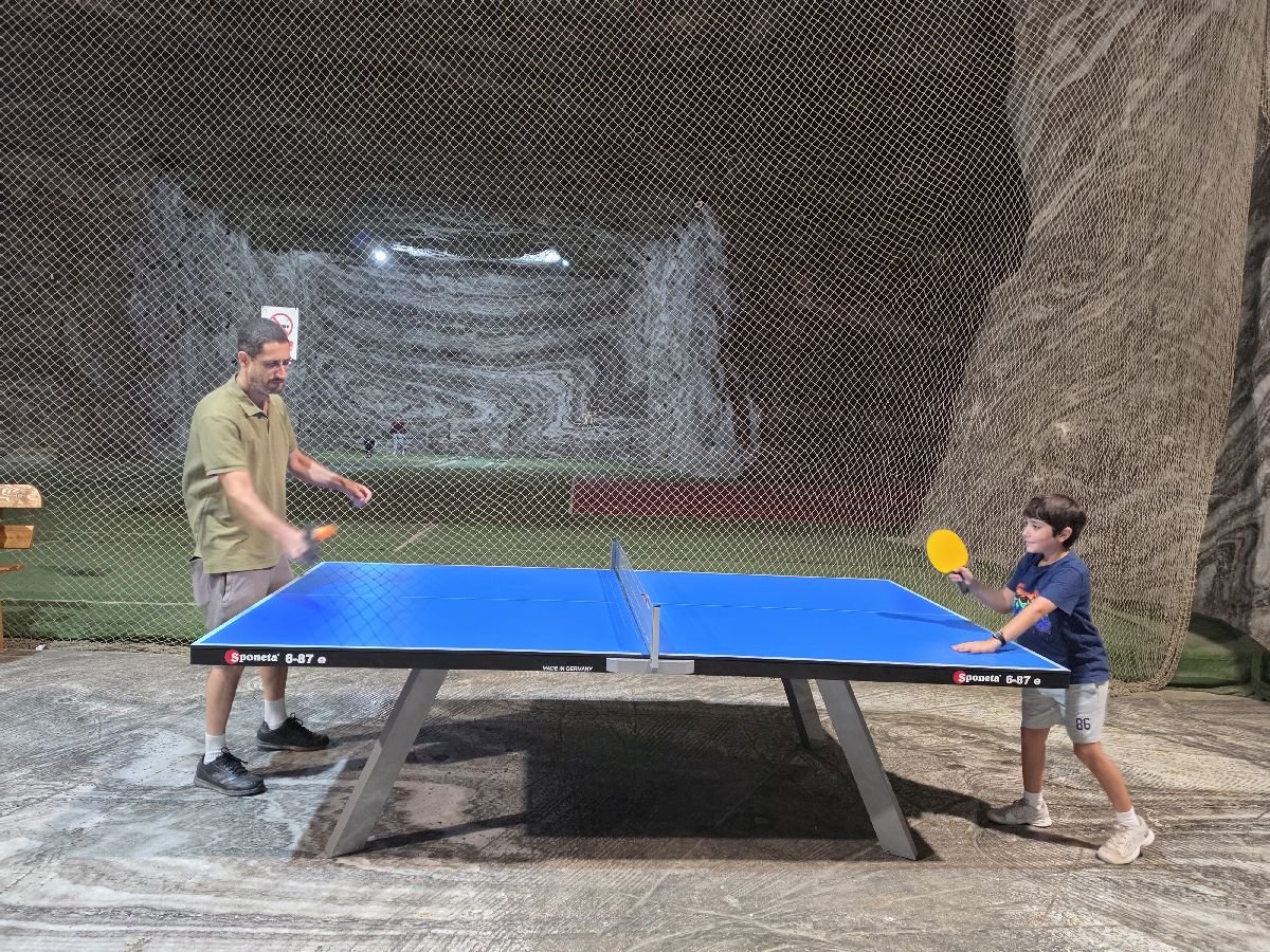 אבא וילד משחקים פינג פונג מתחת לאדמה במכרה המלח ברומניה